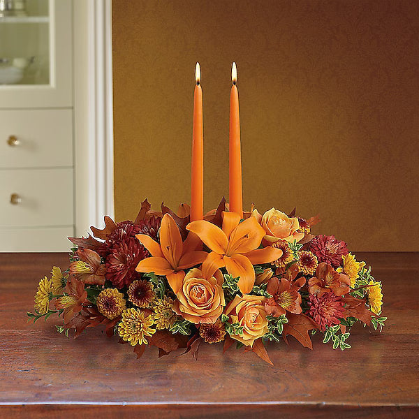 Floral arrangement with orange candles on a wooden surface