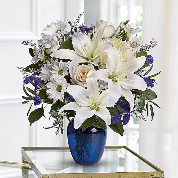 Bouquet of colorful flowers arranged in a blue vase on a glass table