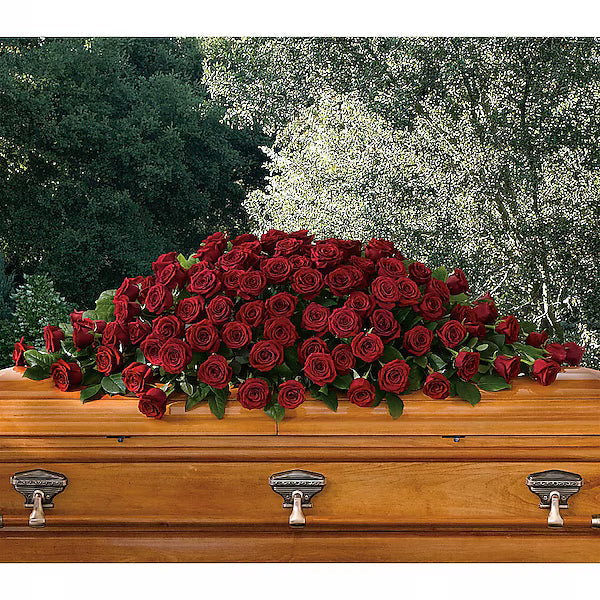 Wooden casket with a large arrangement of red roses against a natural background