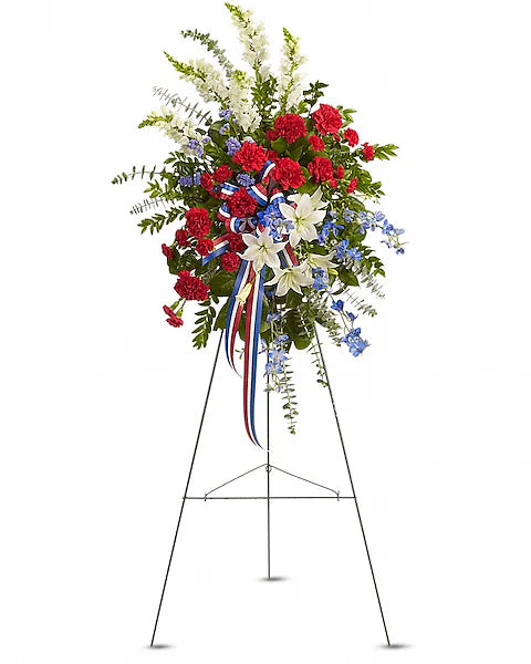 Red, white, and blue floral arrangement on a stand against white background