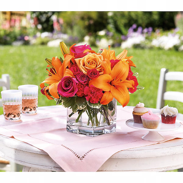 Colorful blossoms beside glasses and cupcakes.