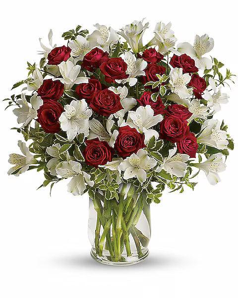 Bouquet of red roses and white lilies in a clear vase on a white background