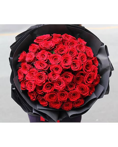 Bouquet of red roses wrapped in black paper on a white background